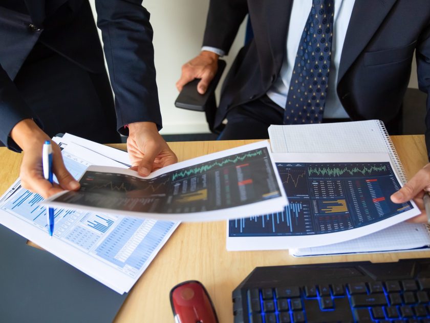 Investor and trader discussing statistic data, holding papers with financial charts and pen. Cropped shot. Broker job or trading concept